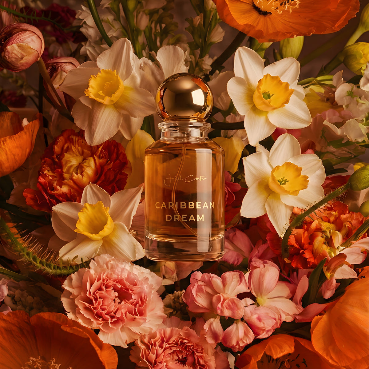 Caribbean Dream perfume bottle with a gold spherical cap surrounded by white, pink and orange flowers.